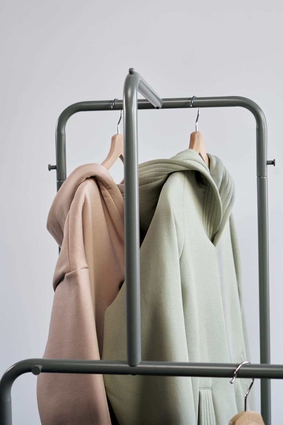 Plain pullover hoodies in soft neutral colours on a clothing rack