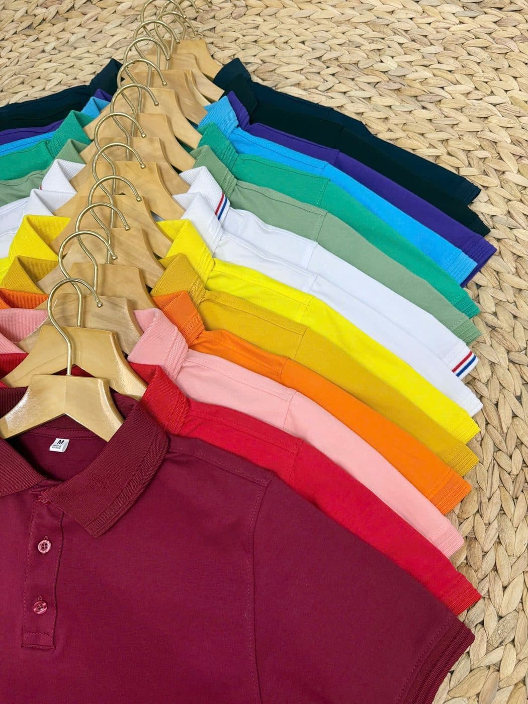 Plain piqué polo shirts in assorted colours on wooden hangers