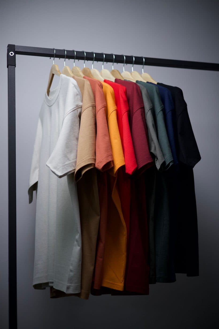 Plain t-shirts in a range of colours hanging on a garment rail