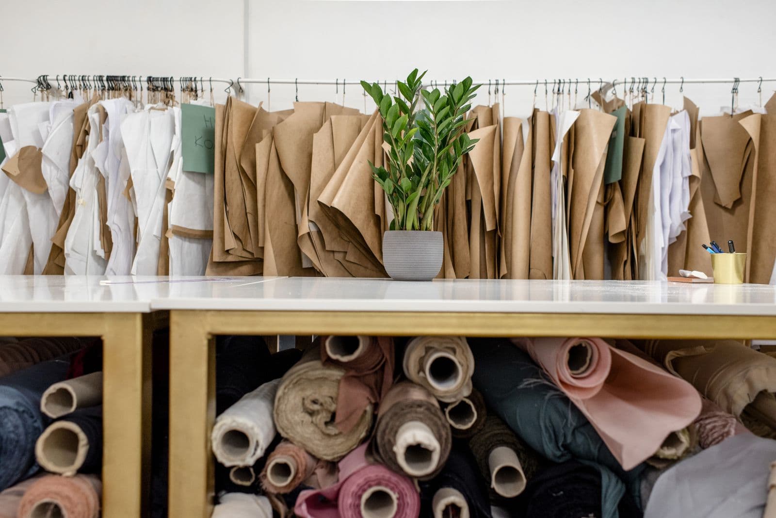Paper patterns hanging above fabric rolls in a pattern room