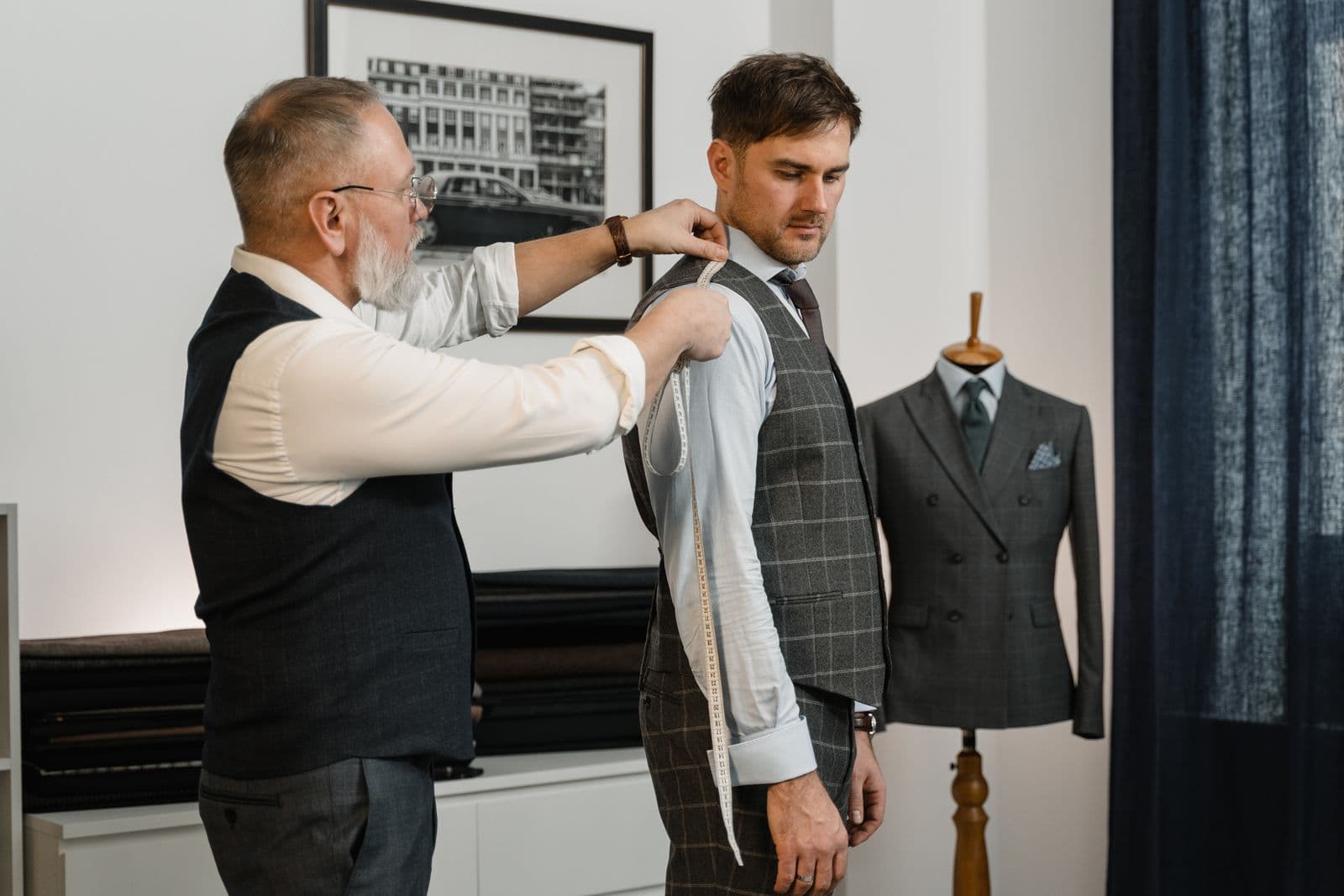 Tailor measuring a men's suit at a fitting